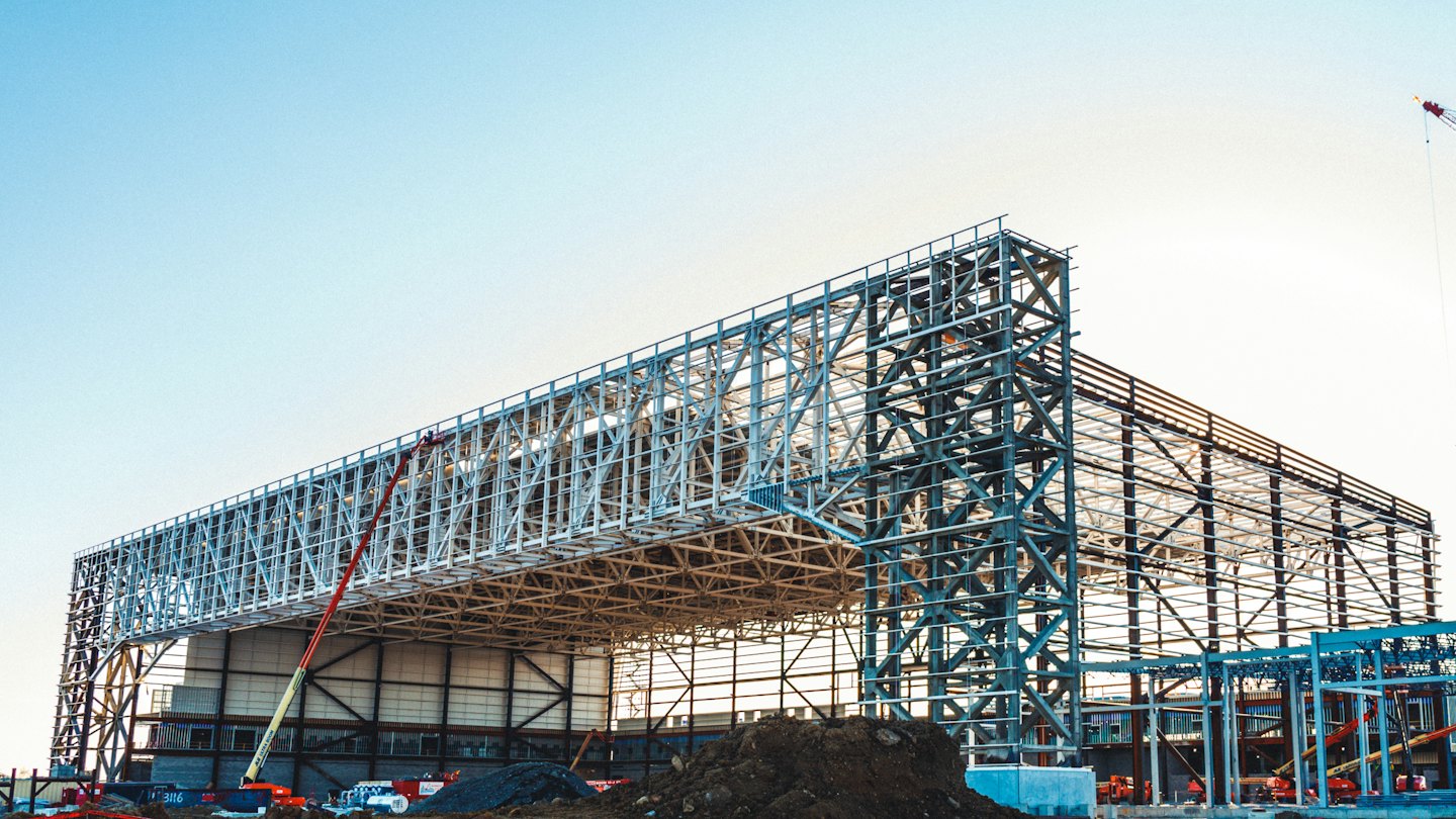 Heavy machinery sits near an industrial building under construction.
