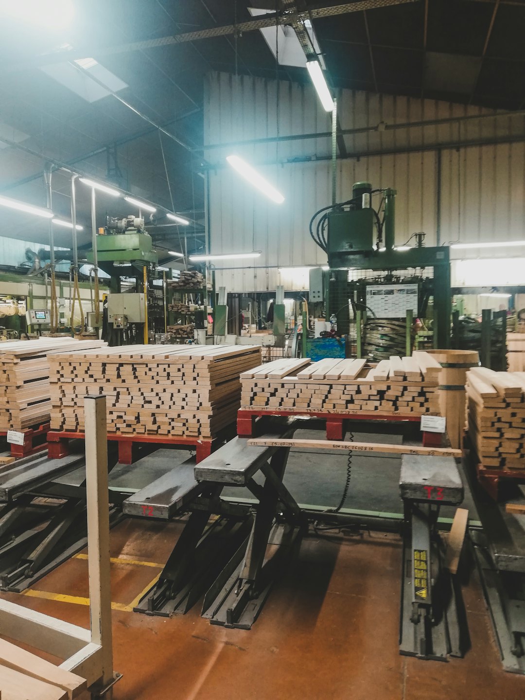 Stacks of wooden planks in a busy woodworking factory.