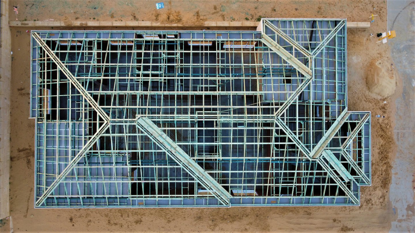 Wooden roof trusses sit atop a house under construction.